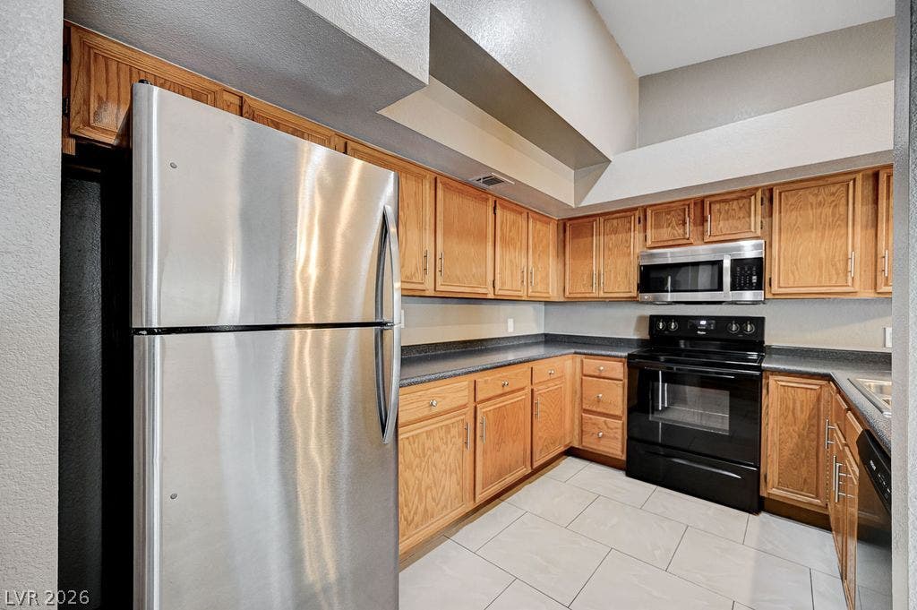 2191 Pinetop Lane, #104, Las Vegas, NV 89119 High vaulted ceilings bring architectural depth to this kitchen finished with classic oak cabinetry.