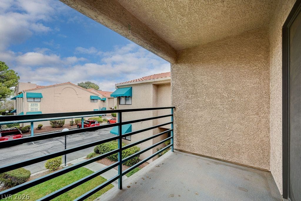 2191 Pinetop Lane, #104, Las Vegas, NV 89119 A private covered balcony features durable concrete flooring, textured stucco walls, and metal railings.