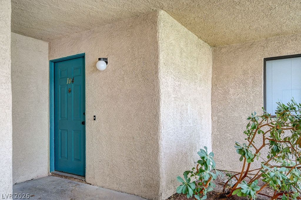 2191 Pinetop Lane, #104, Las Vegas, NV 89119 A private covered entryway leads to a welcoming front door set against textured stucco walls.