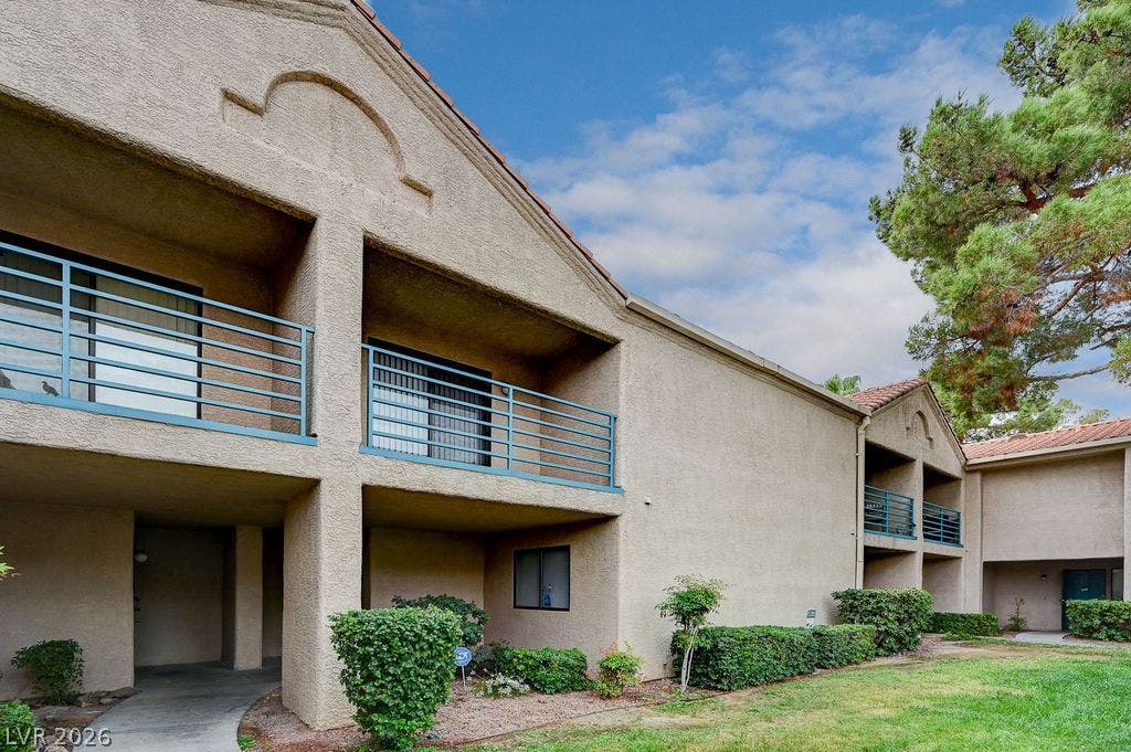 2191 Pinetop Lane, #104, Las Vegas, NV 89119 Classic stucco exterior showcases private balconies overlooking structured green lawns under a bright sky.
