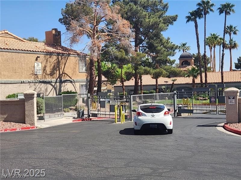 5220 Mission Carmel Lane, #104, Las Vegas, NV 89107 View of asphalt street featuring a gated entry, curbs, and a gate