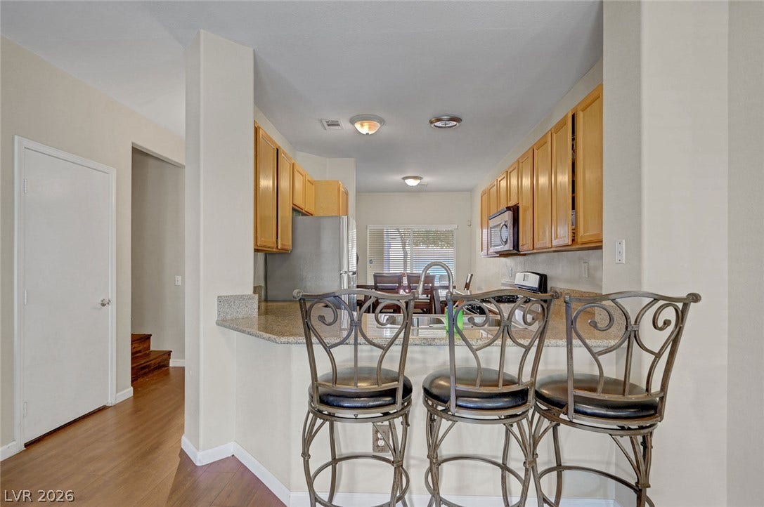 7450 S Eastern Avenue, #1064, Las Vegas, NV 89123 Rich wood flooring complements stone countertops in this open concept kitchen design.