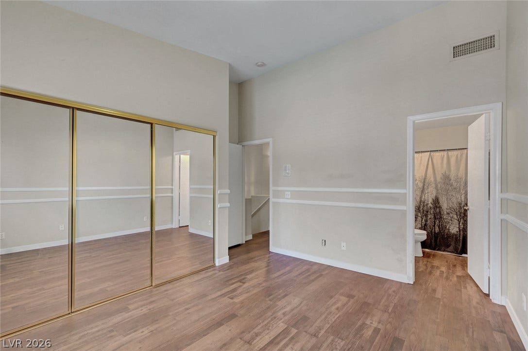 7450 S Eastern Avenue, #1064, Las Vegas, NV 89123 High ceilings and warm wood floors enhance this bedroom featuring mirrored closet doors.