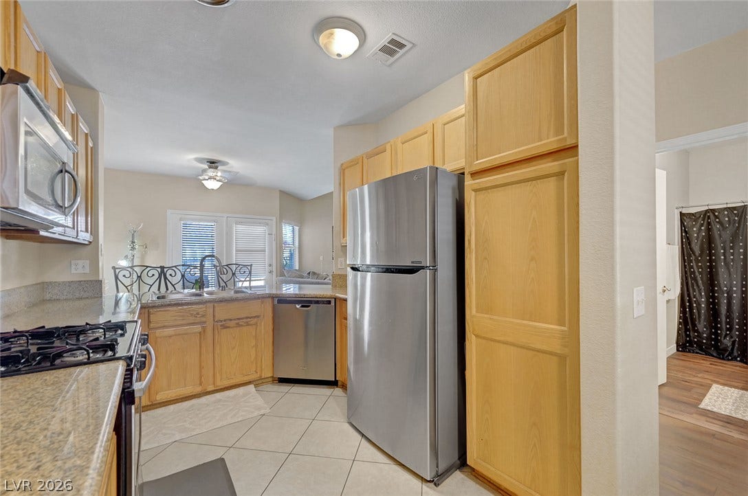 7450 S Eastern Avenue, #1064, Las Vegas, NV 89123 Gleaming stone countertops and classic wood cabinetry enrich this well-designed culinary workspace.