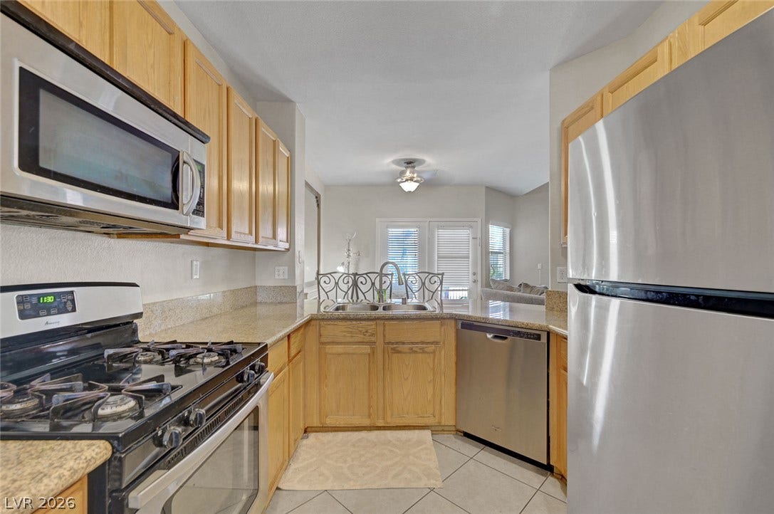 7450 S Eastern Avenue, #1064, Las Vegas, NV 89123 Natural wood cabinetry and granite countertops frame this functional kitchen layout.