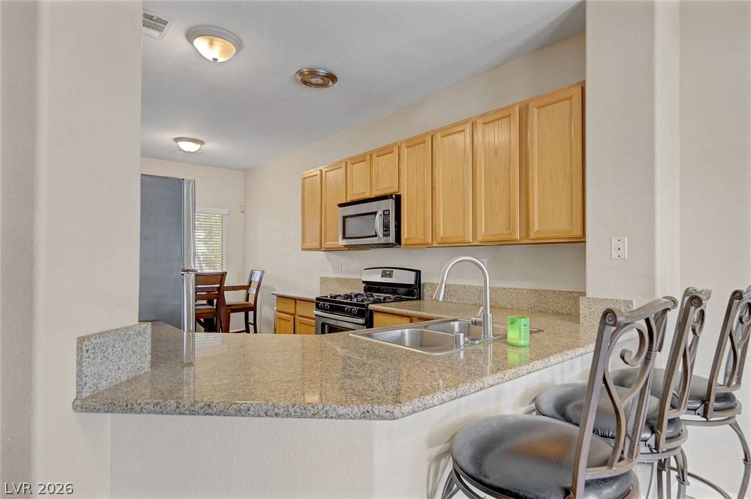 7450 S Eastern Avenue, #1064, Las Vegas, NV 89123 Granite countertops and warm wood cabinetry define this functional, open-concept kitchen space.