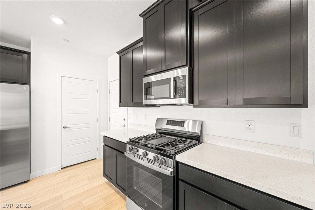 9568 Sagebrush Grove Street, Las Vegas, NV 89178 Dark cabinetry contrasts beautifully with light stone countertops and clean plank flooring.