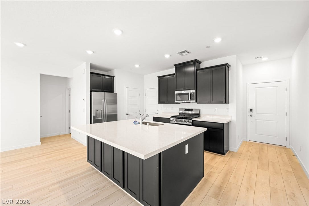 9568 Sagebrush Grove Street, Las Vegas, NV 89178 Sleek dark cabinetry anchors this modern culinary space featuring a large central island and hardwood flooring.