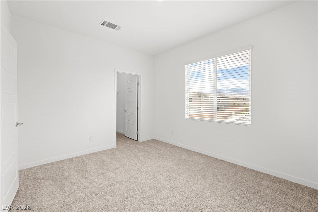 9568 Sagebrush Grove Street, Las Vegas, NV 89178 A spacious bedroom features soft neutral carpeting and a large window framing distant mountain views.