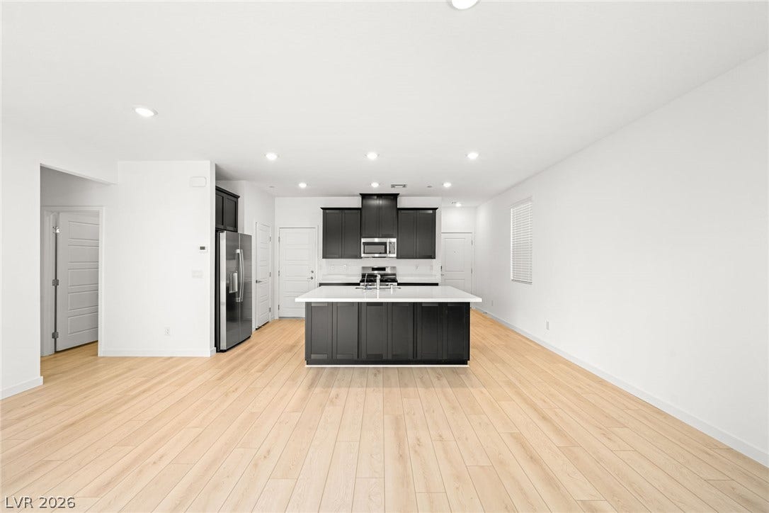 9568 Sagebrush Grove Street, Las Vegas, NV 89178 Gleaming wood floors anchor this open-concept culinary space featuring a dark-cabinet island.