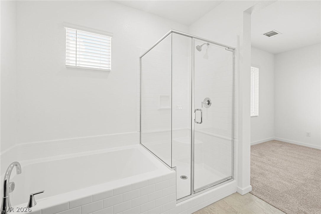9568 Sagebrush Grove Street, Las Vegas, NV 89178 A glass-enclosed shower stands alongside a tiled soaking tub under crisp white walls.
