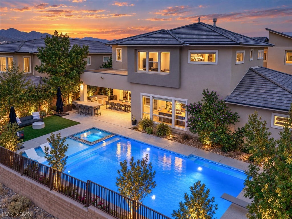 2999 The Peaks Lane, Las Vegas, NV 89138 An inviting backyard oasis centers around a glowing swimming pool beneath a vibrant sunset sky.