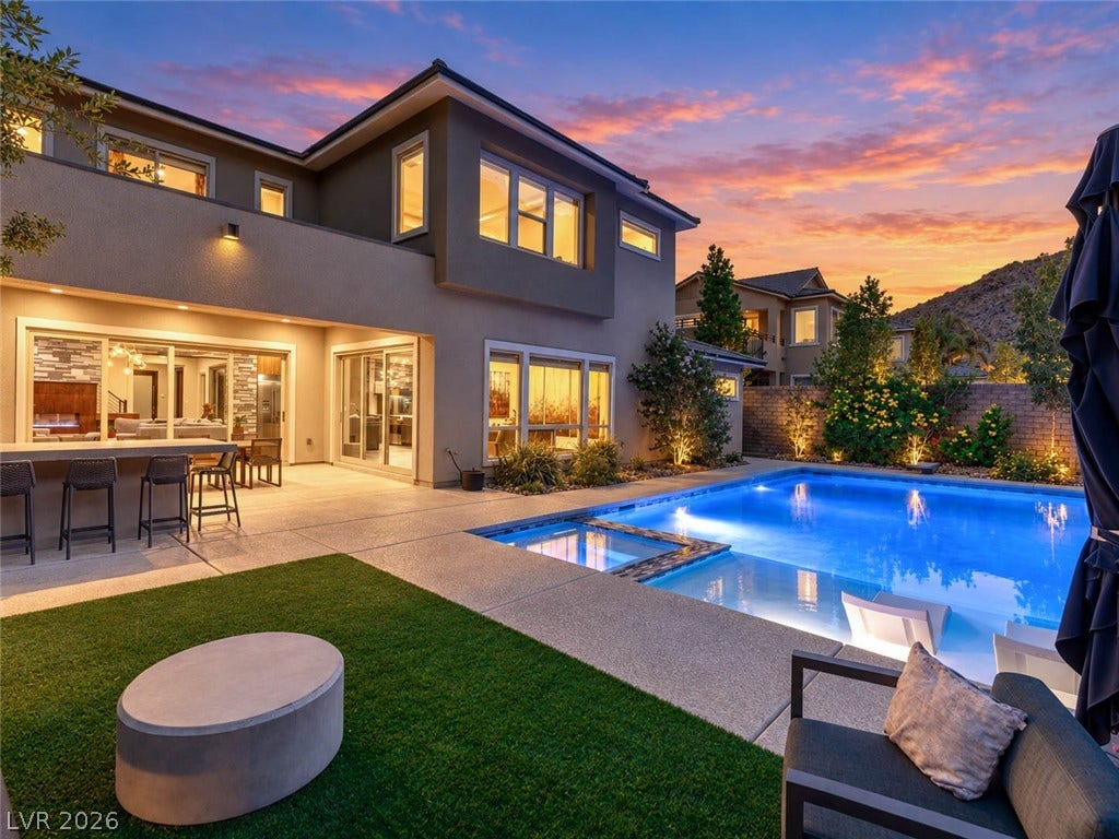2999 The Peaks Lane, Las Vegas, NV 89138 An inviting backyard oasis features a modern swimming pool and integrated spa under sunset skies.