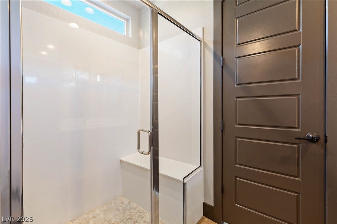 2999 The Peaks Lane, Las Vegas, NV 89138 Downstairs en-suite bathroom features glass doors, built-in seating, and stone tile flooring.