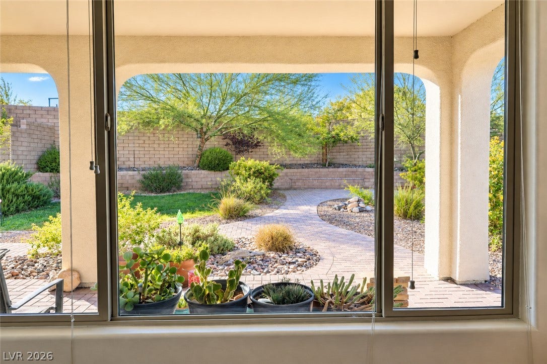11886 Corenzio Avenue, Las Vegas, NV 89138 Large picture windows frame a tranquil view of the landscaped backyard and paved path.