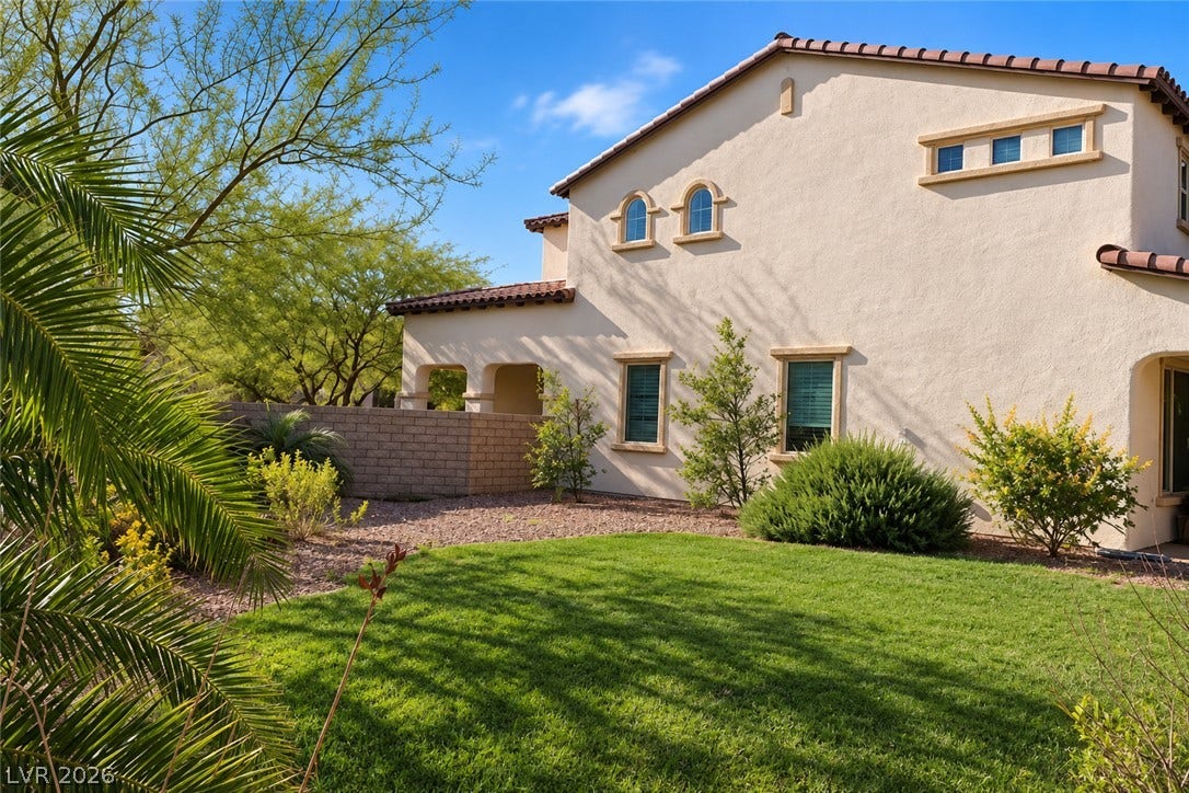 11886 Corenzio Avenue, Las Vegas, NV 89138 Manicured green turf highlights this private backyard space alongside the stucco exterior.
