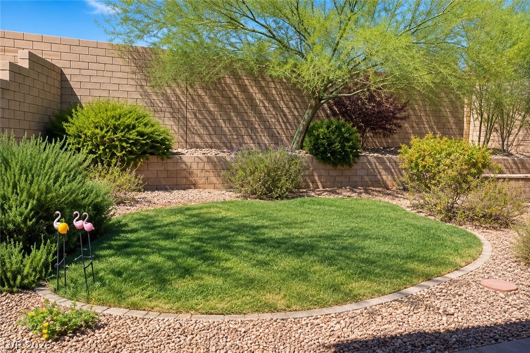 11886 Corenzio Avenue, Las Vegas, NV 89138 A circular green lawn creates a striking focal point amidst the surrounding desert gravel landscaping.