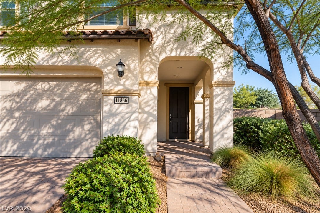11886 Corenzio Avenue, Las Vegas, NV 89138 An arched covered entry welcome guests alongside the paved driveway and neat desert landscaping.