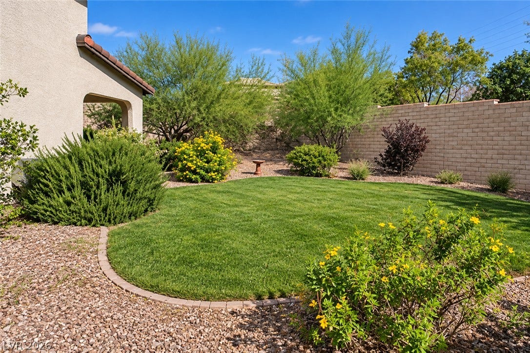11886 Corenzio Avenue, Las Vegas, NV 89138 Lush green turf highlights this private backyard surrounded by mature plantings and block fencing.