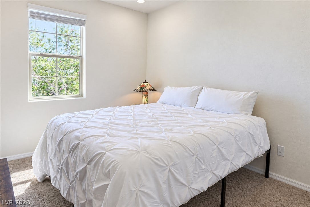 11886 Corenzio Avenue, Las Vegas, NV 89138 Natural light fills this peaceful bedroom featuring plush carpet and a garden-facing window.