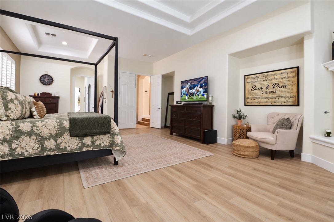 10 Caminito Amore, Henderson, NV 89011 Multi-layered tray ceilings and expansive wood-style flooring elevate this spacious main bedroom suite.