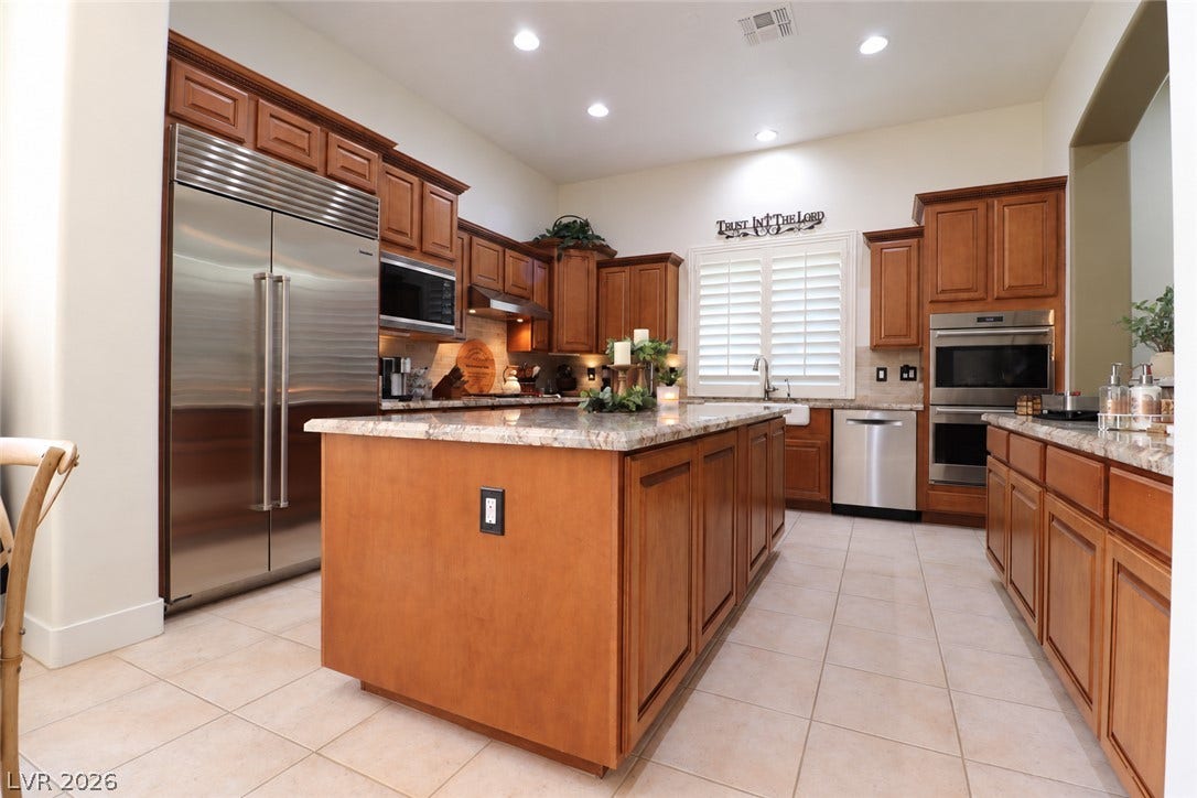 10 Caminito Amore, Henderson, NV 89011 Gleaming stone countertops and warm wood cabinetry elevate this open chef's kitchen.