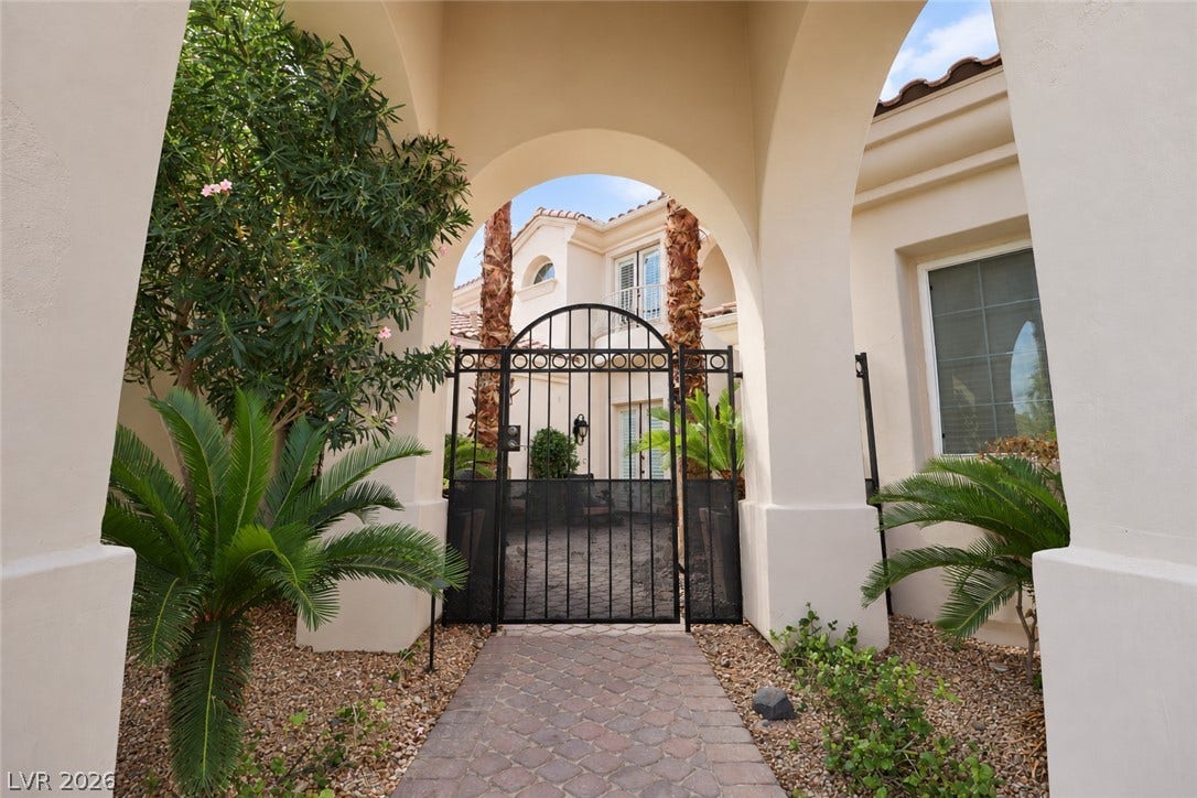 10 Caminito Amore, Henderson, NV 89011 Stately stucco archways and a secure gated entry frame the welcoming paved courtyard pathway.