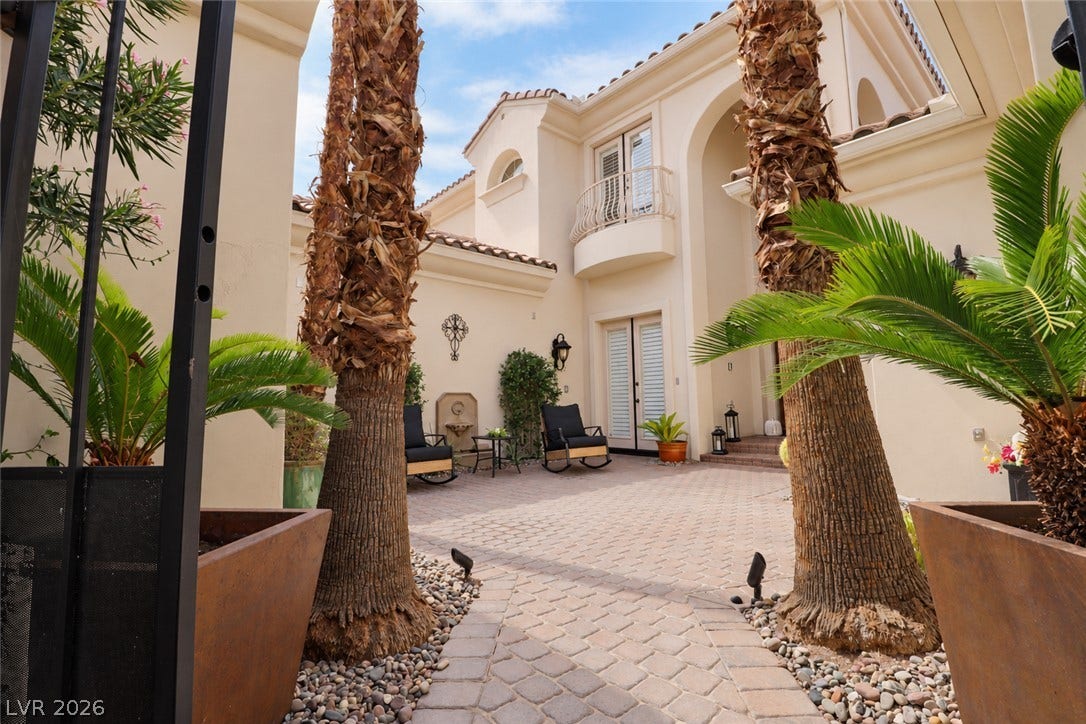 10 Caminito Amore, Henderson, NV 89011 An inviting stone-paved entryway is framed by towering palm trees and classic Mediterranean architecture.