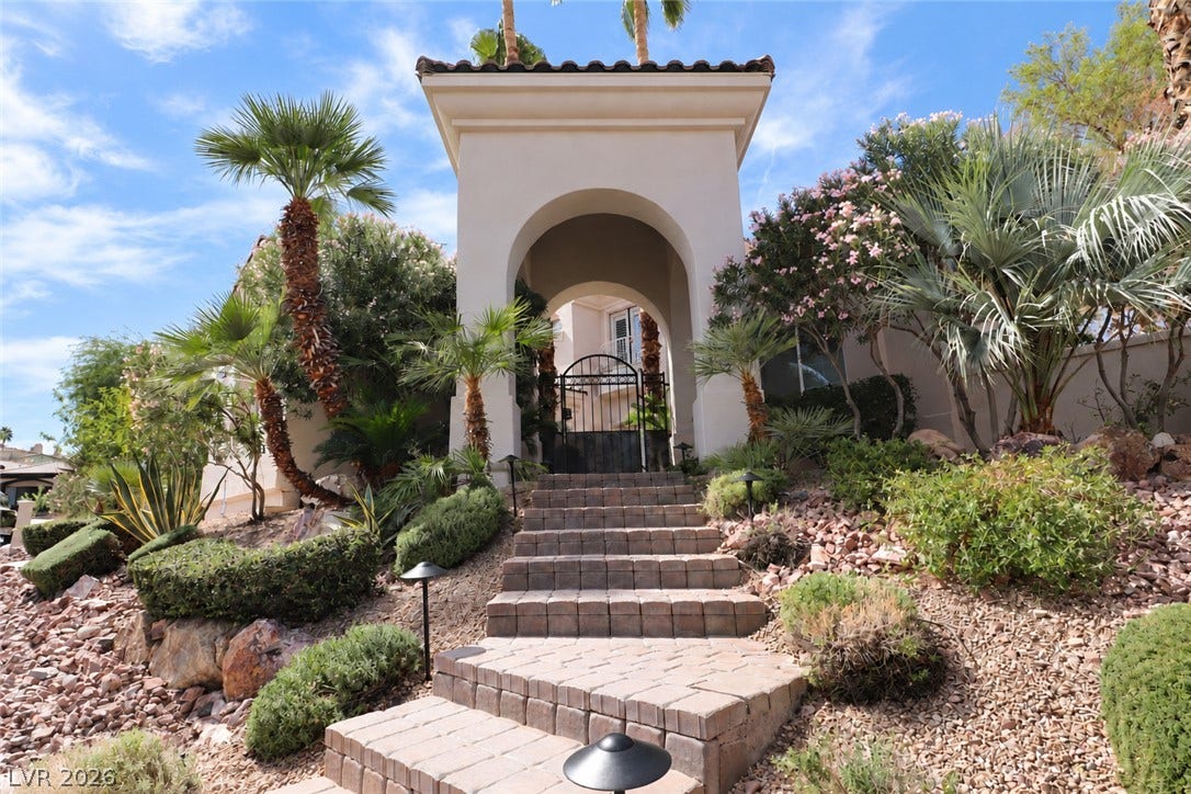 10 Caminito Amore, Henderson, NV 89011 An arched entry portico and stone steps lead toward the gated private courtyard.