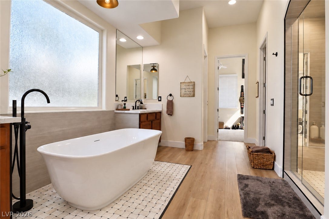 10 Caminito Amore, Henderson, NV 89011 A modern soaking tub stands on tiled accents alongside warm wood flooring.