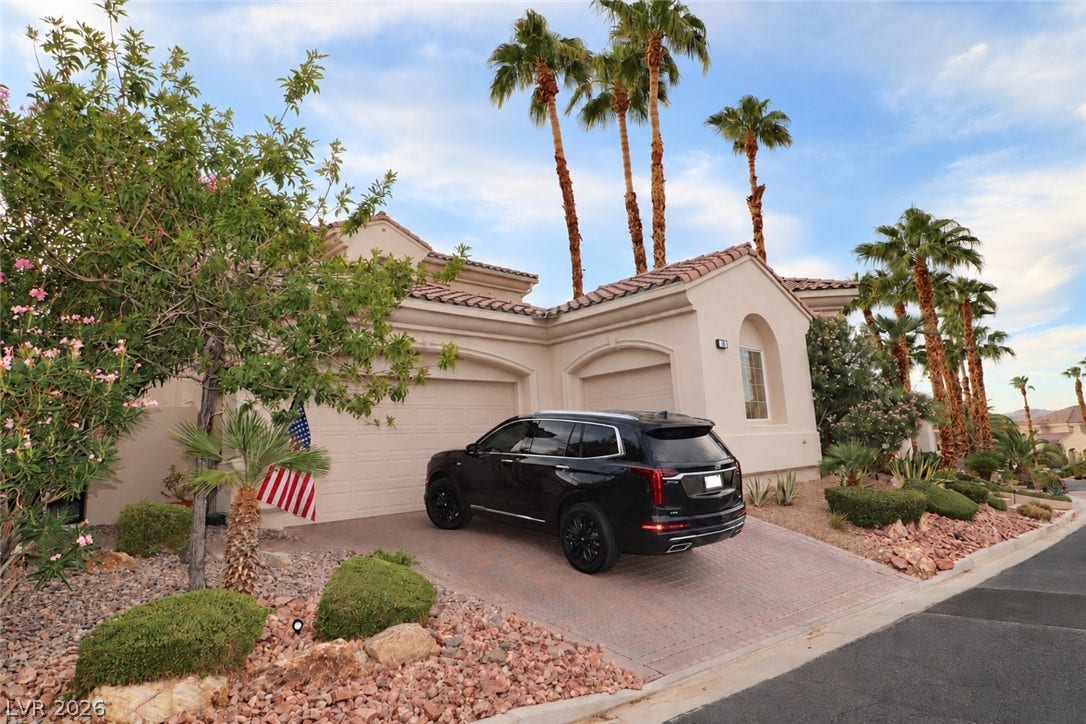 10 Caminito Amore, Henderson, NV 89011 Elegant Mediterranean-inspired architecture pairs with mature palm trees and a paved driveway.
