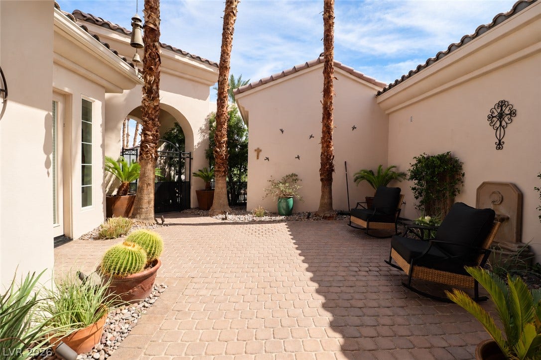 10 Caminito Amore, Henderson, NV 89011 An inviting paved courtyard lined by textured stucco walls under clear desert skies.
