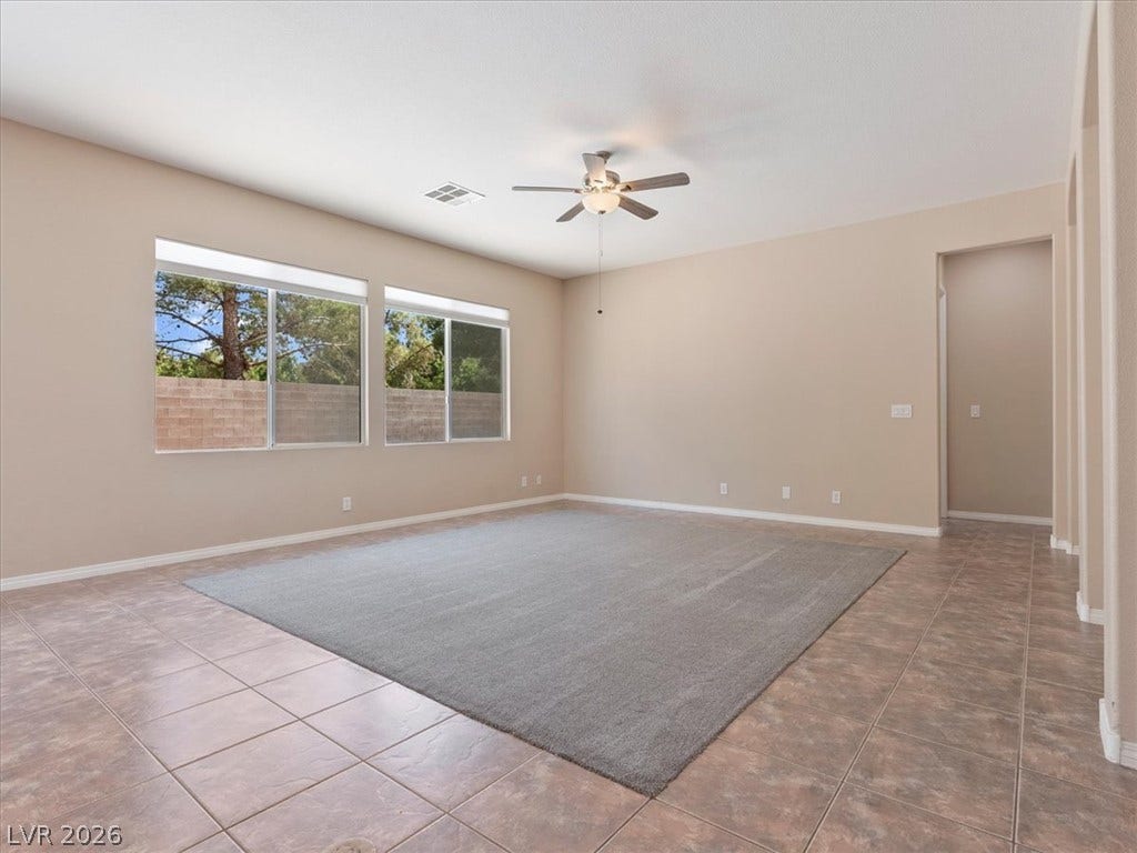 1217 Silent Sunset Avenue, North Las Vegas, NV 89084 Ample natural light streams through wide windows into a spacious room with tile flooring.