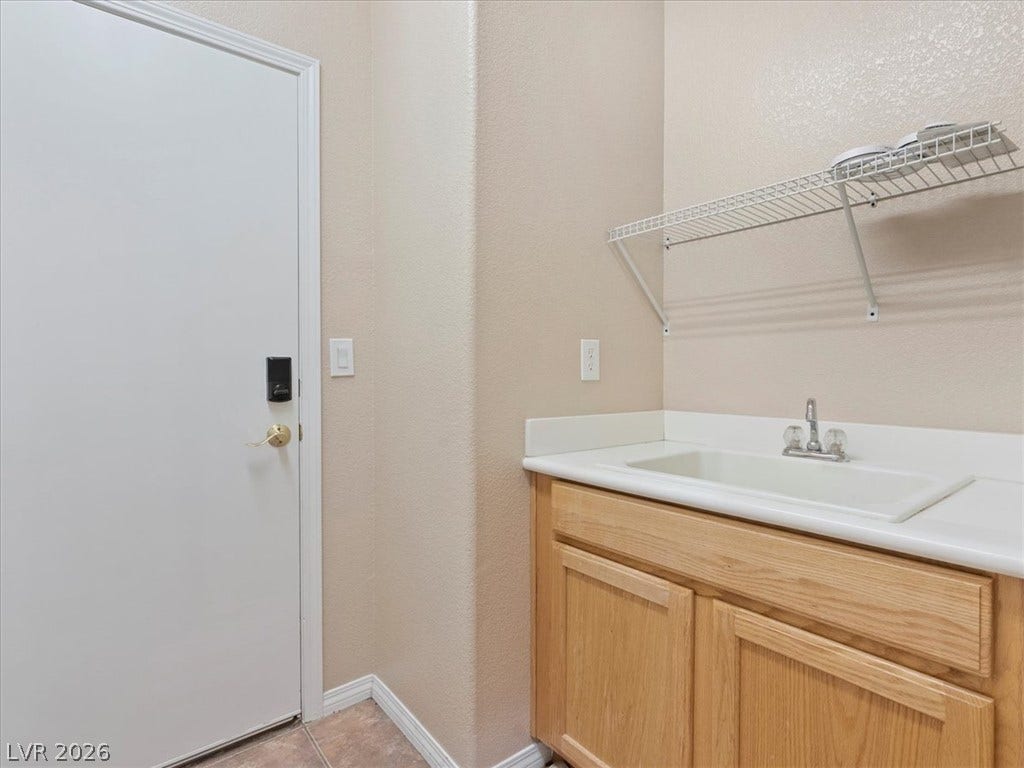 1217 Silent Sunset Avenue, North Las Vegas, NV 89084 A functional laundry area features a built-in utility sink cabinet and wire shelving.