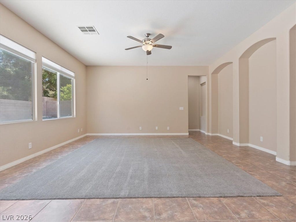 1217 Silent Sunset Avenue, North Las Vegas, NV 89084 Arched wall niches and tile flooring with carpet inlay highlight this airy living room.