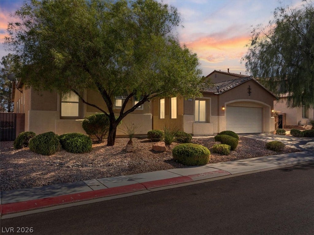 1217 Silent Sunset Avenue, North Las Vegas, NV 89084 Desert landscaping and a tiled roof enhance this elegant stucco home at sunset.