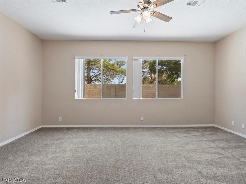 1217 Silent Sunset Avenue, North Las Vegas, NV 89084 Plush carpeting and wide windows frame pleasant backyard views in this comfortable bedroom.