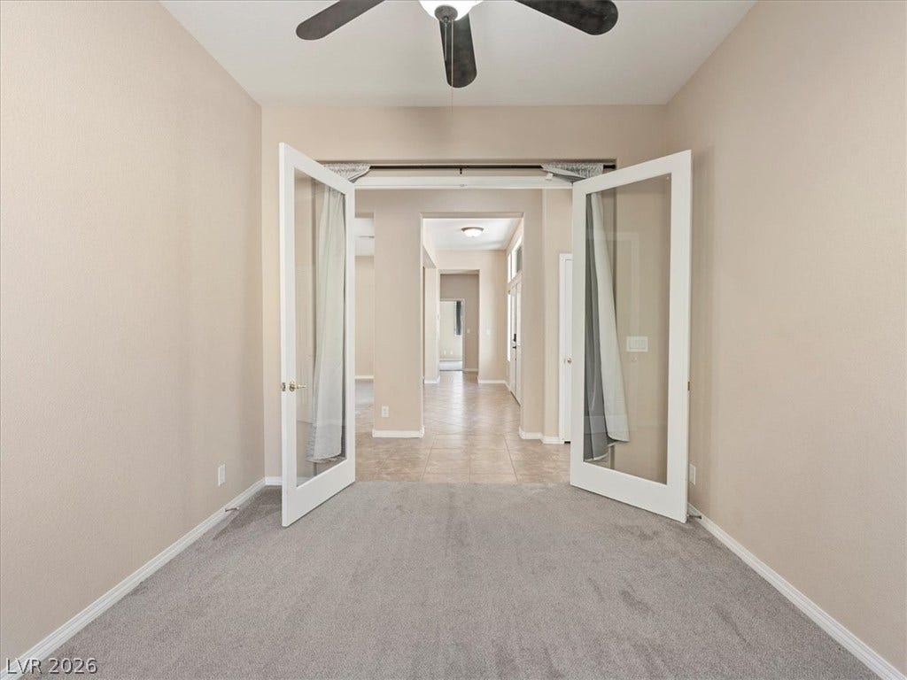 1217 Silent Sunset Avenue, North Las Vegas, NV 89084 Double glass doors open to reveal an adjoining tiled hallway from this carpeted room.
