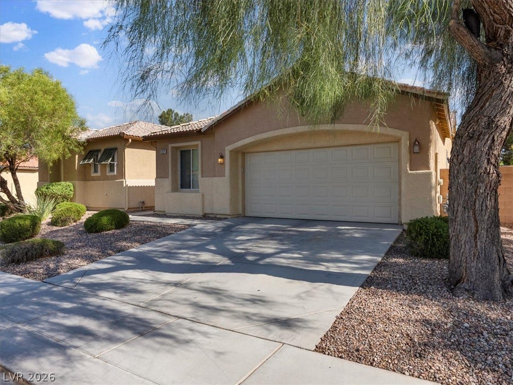 1217 Silent Sunset Avenue, North Las Vegas, NV 89084 A spacious concrete driveway leads directly to the attached two-car garage under desert-friendly landscaping.