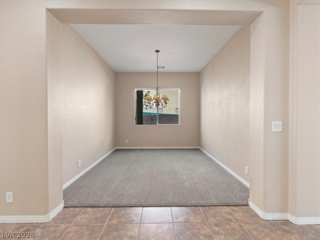 1217 Silent Sunset Avenue, North Las Vegas, NV 89084 An arched transition leads into a dedicated dining area featuring classic lighting and carpeted flooring.