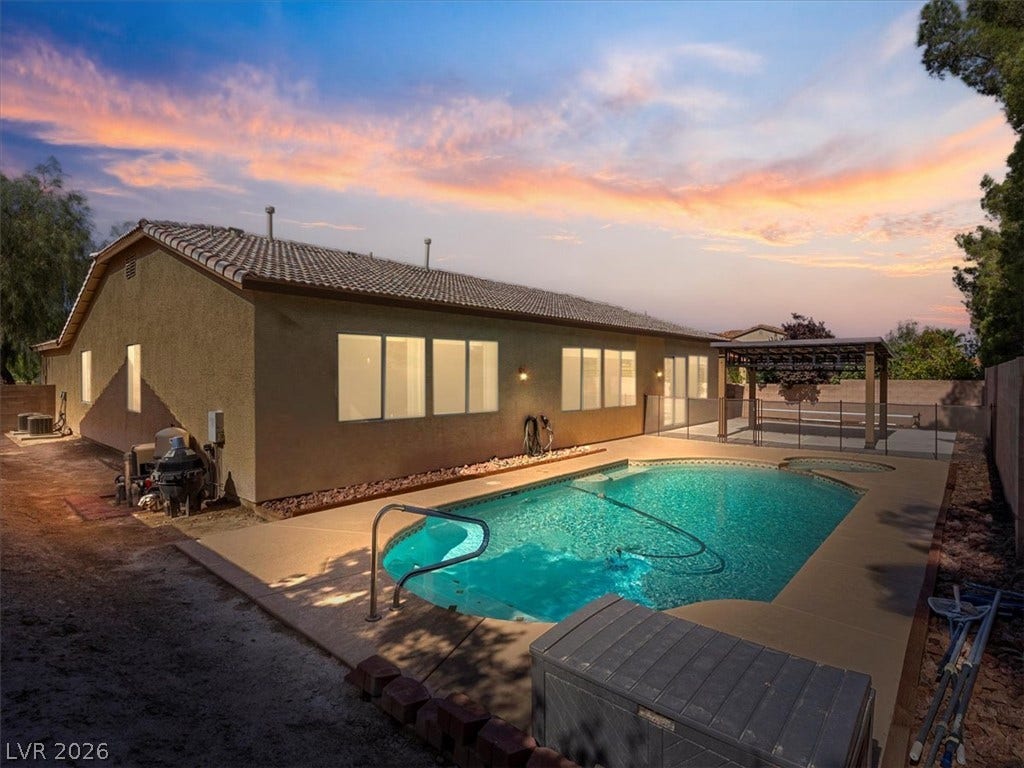 1217 Silent Sunset Avenue, North Las Vegas, NV 89084 An inviting backyard oasis features a shimmering inground pool under a twilight sky.