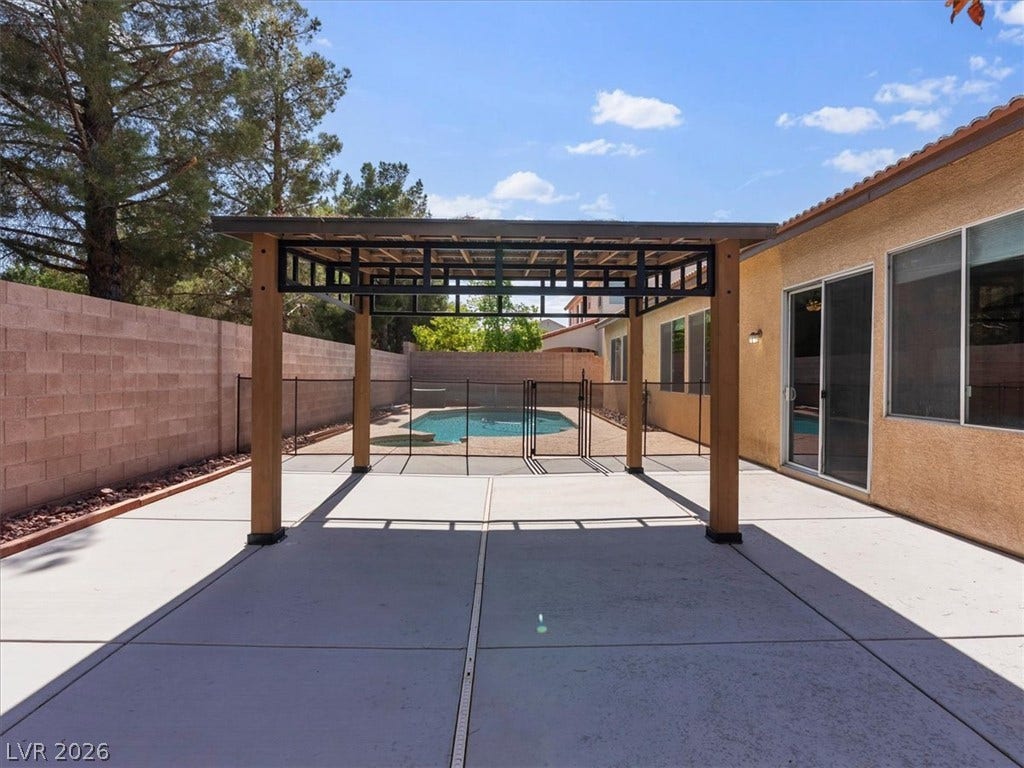 1217 Silent Sunset Avenue, North Las Vegas, NV 89084 An inviting backyard patio features a sturdy wooden pergola overlooking a fenced-in swimming pool.
