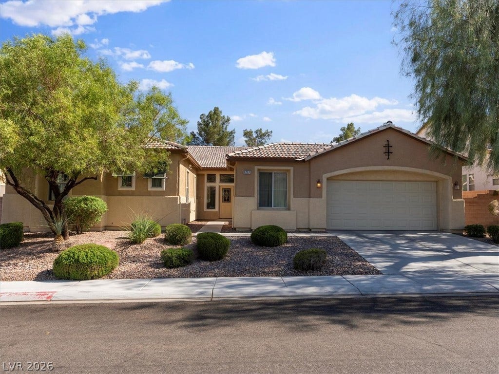 1217 Silent Sunset Avenue, North Las Vegas, NV 89084 A classic stucco exterior features a tiled roof and an attached garage.