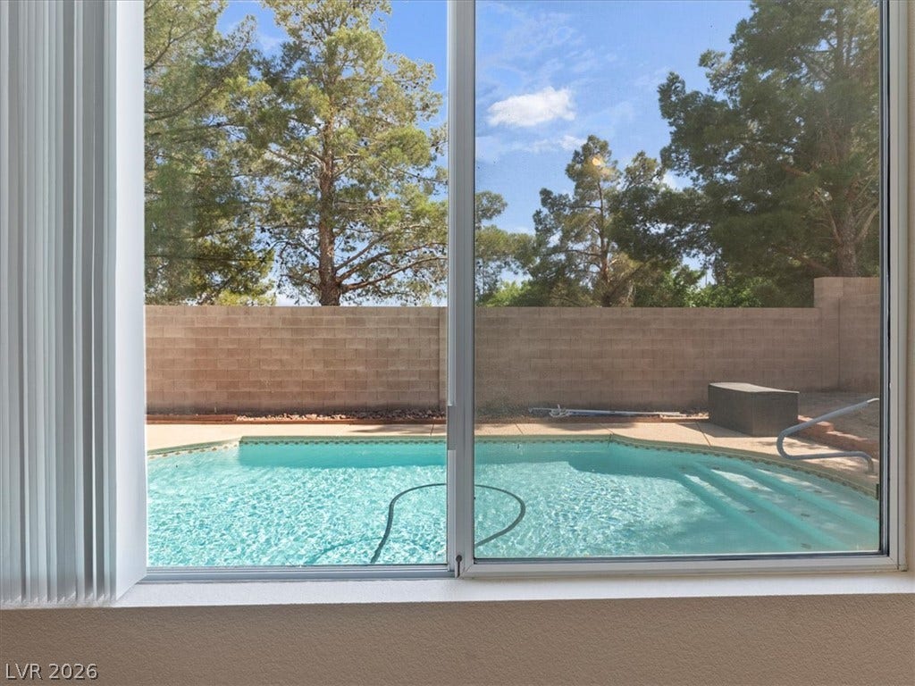 1217 Silent Sunset Avenue, North Las Vegas, NV 89084 Large sliding glass doors overlook a sparkling pool and a private, walled backyard.