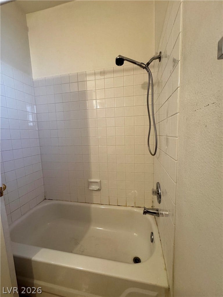 1900 N Torrey Pines Drive, #101, Las Vegas, NV 89108 A classic bathtub and shower combination features traditional white tiled walls.