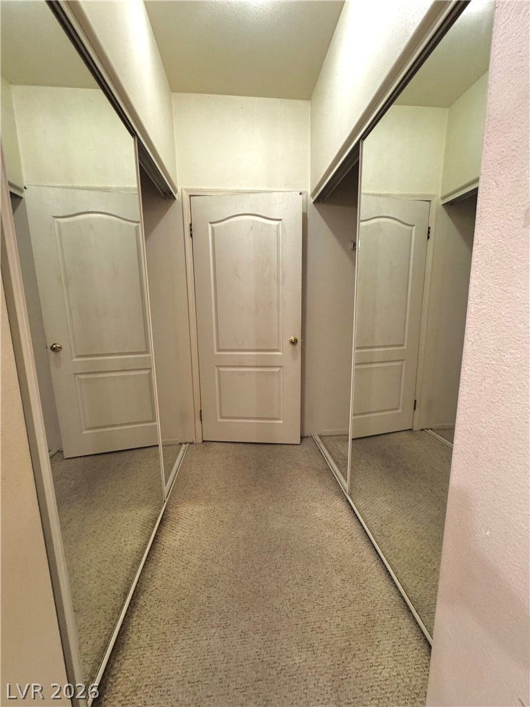 1900 N Torrey Pines Drive, #101, Las Vegas, NV 89108 Mirrored wardrobe doors flank a carpeted dressing corridor leading to a private paneled door.