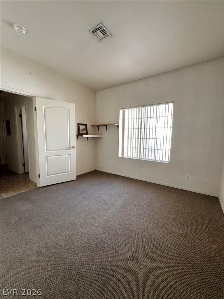 1900 N Torrey Pines Drive, #101, Las Vegas, NV 89108 Wall-to-wall carpeting and a wide window with vertical blinds anchor this versatile bedroom space.