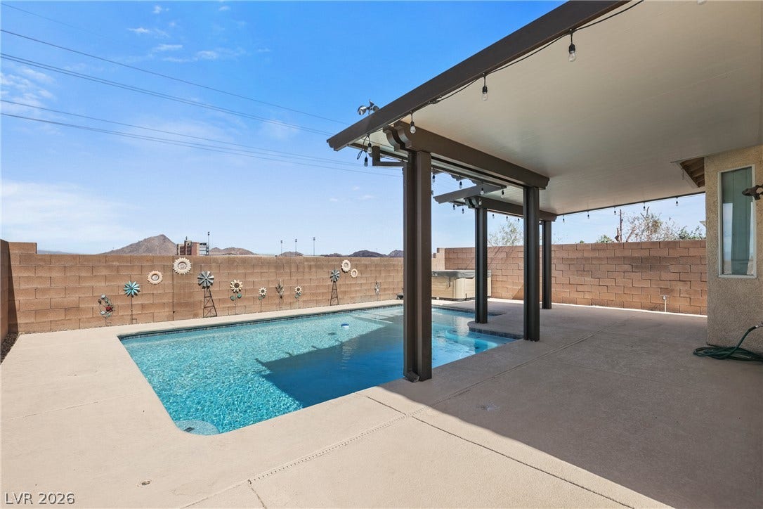 7066 Shimmering Avenue, Henderson, NV 89011 A spacious covered patio overlooks a refreshing backyard swimming pool set against mountain views.