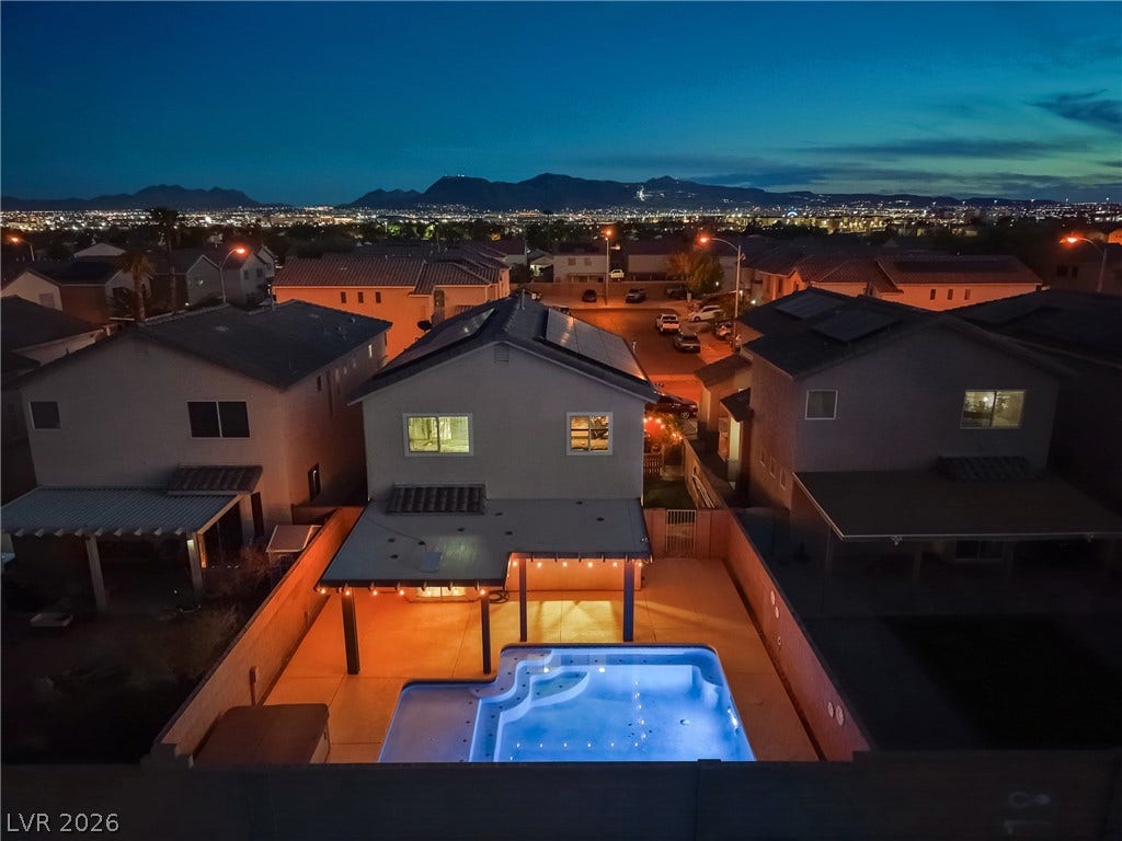 7066 Shimmering Avenue, Henderson, NV 89011 Glittering city lights and mountain contours frame the backyard pool at twilight.