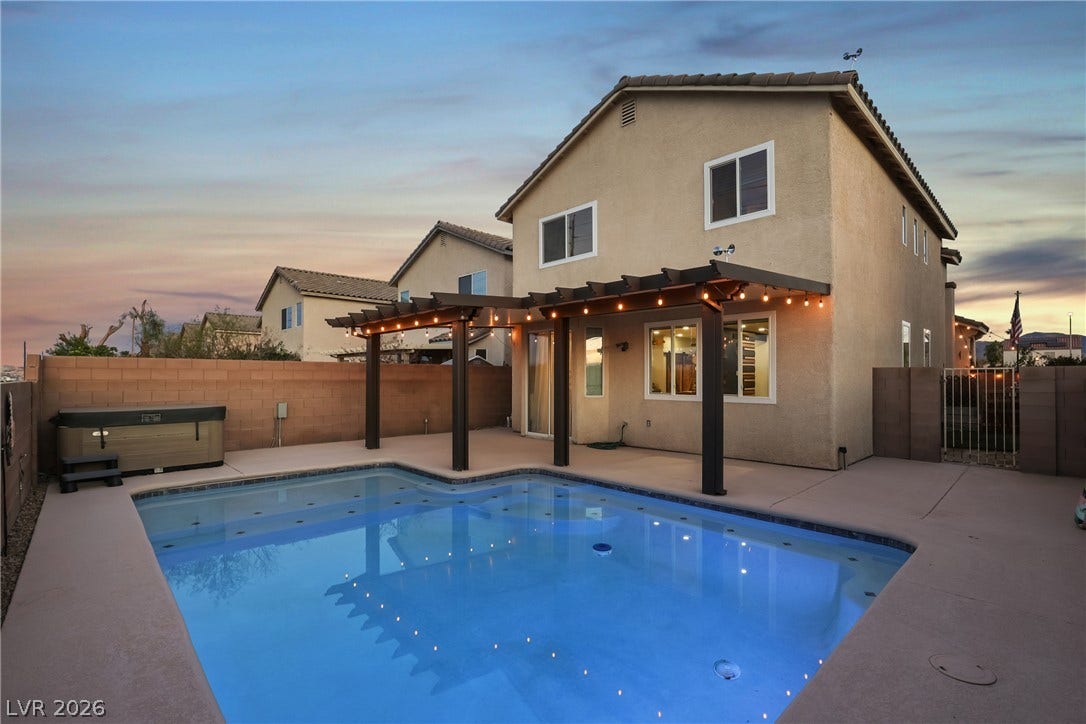 7066 Shimmering Avenue, Henderson, NV 89011 An inviting backyard oasis features a sparkling swimming pool, built-in pergola, and a private spa.